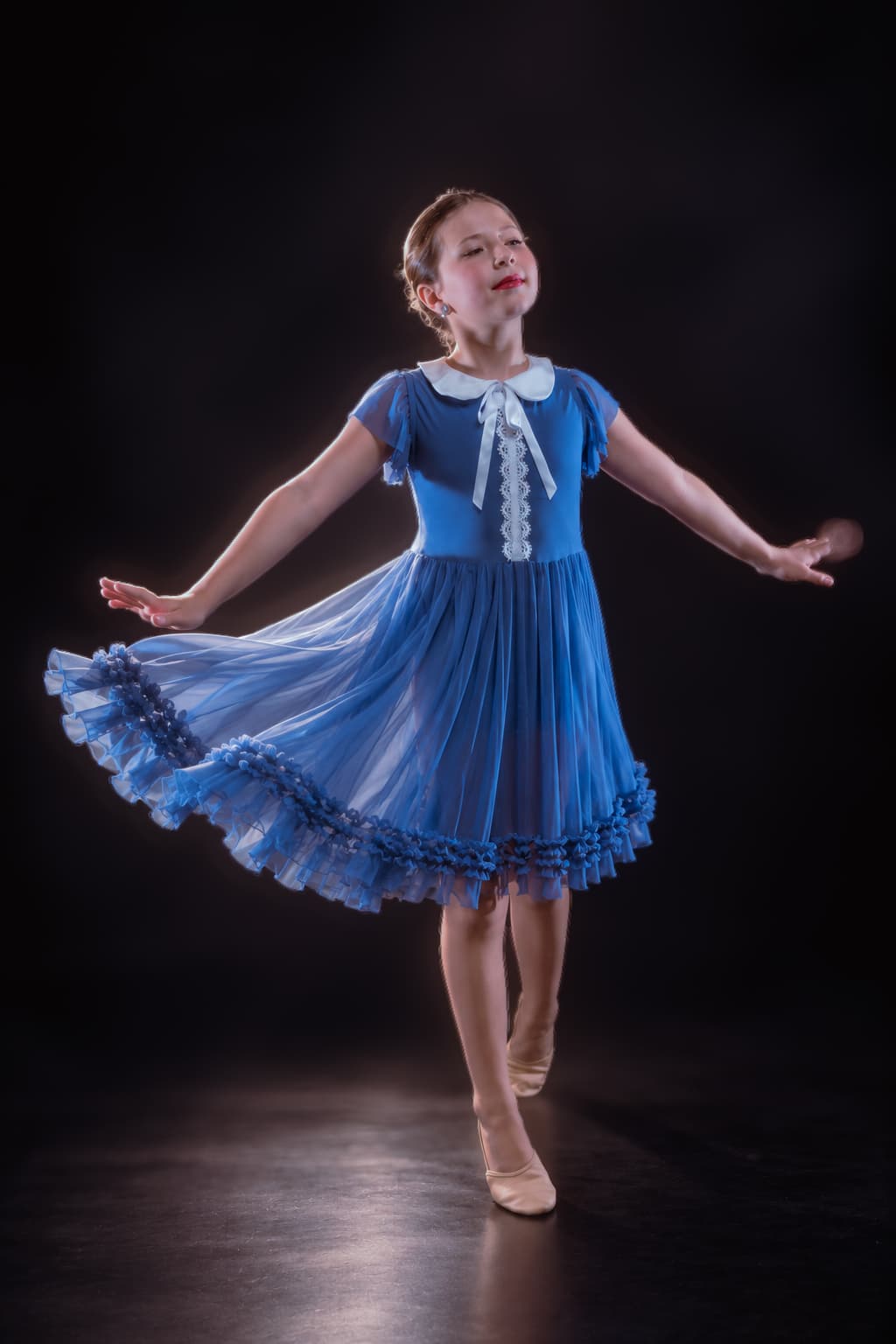 Dancer in blue dress photographed with theatrical studio lighting